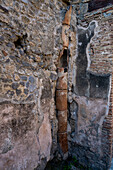 Ein zerbrochenes Abflussrohr aus Keramik in der Wand des Gebäudes I.7.8 in den antiken römischen Ruinen von Pompeji, Italien.