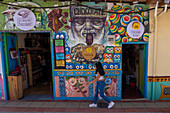 A young woman walks in front of the colorfully-painted wall of a shop in the tourist town of Guatape, Colombia.