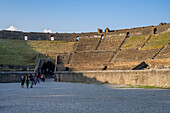 Tourists in the arena of the Amphitheater of Pompeii in the ancient Roman ruins of Pompeii in Italy.