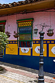 Bunt bemalte Holzarbeiten und ein 3-D-Wandbild aus Gips oder Zócalo an der Wand eines Hostals in Guatape, Kolumbien.