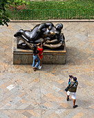 Girls being photographed by the Reclining Woman statue in the Botero Plaza in Medellin, Colombia.