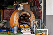 A gas-fired clay oven in a shop selling fast food for take-out on the street in Rionegro, Colombia.