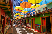 Colorful parasols provide shade on the Plazoleta de los Zócalos, a shopping street in Guatape, Colombia.