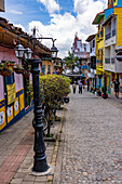 Metal lamppost & colorfully-painted buildings on a cobblestone street in the tourist town of Guatape, Colombia.