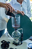Adding freshly-ground coffee to a siphon coffee maker during a tour of a coffee farm in Colombia.