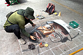 An artist drawing a portrait with chalk on the sidewalk in downtown Medellin, Colombia.