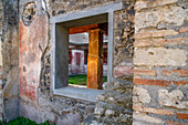Blick durch ein Fenster in das Atrium des Hauses von Julia Felix, Gebäude II.4.3 in den antiken römischen Ruinen von Pompeji, Italien.