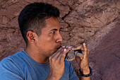 A young indigenous man plays a condor-shaped ocarina at the Amphitheater in Quebrada de las Conchas, Argentina.