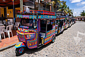 Eine Reihe farbenfroher Motochivas oder Mototaxis, touristische Verkehrsmittel in der Stadt Guatape, Kolumbien.