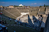 Tourists in the Large Theater, Building VIII.7.20, in the ancient Roman ruins of Pompeii, Italy.