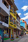 Tourists and colorfully-painted buildings along a street in the tourist town of Guatape, Colombia.