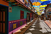 Colorful parasols provide shade on the Plazoleta de los Zócalos, a shopping street in Guatape, Colombia.