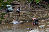 Homeless men washing themselves and their clothes in the Cali River in Cali, Colombia.