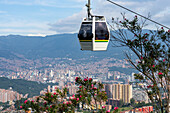 A gondola of the Medellin Metrocable system with downtown Medellin Colombia in the background.