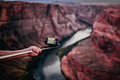 Close up of hand holding a smartphone with a stick to photograph Horseshoe bend, a horseshoe-shaped incised meander of the Colorado River, Glen Canyon, Arizona