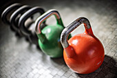 Bunte Kettlebells sind in einem Fitnessstudio aufgereiht, bereit für eine Trainingseinheit. Das Abendlicht schafft eine einladende Atmosphäre.