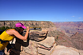 Junge Frau mit Suchgerät und Fernrohr am Rande des Grand Canyon
