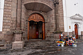 The main portal of the Church of Santo Domingo on Santo Domingo Plaza in the historic center of Quito, Ecuador. Women sell flowers & rosary beads outside.