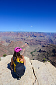 Sitting young woman enjoying the views of Grand Canyon, Arizona