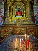 Brennende Kerzen an einem kunstvollen Altarbild in einer Seitenkapelle in der Basilika Unserer Lieben Frau von der Barmherzigkeit in Quito, Ecuador.