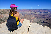 Sitting young woman enjoying the views of Grand Canyon, Arizona