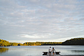 Man and woman walking on jetty in front of lake