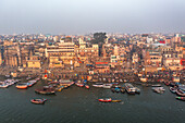 Aerial view of the bustling Ganges river with colorful ghats and boats, Varanasi, Uttar Pradesh, India.
