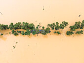 Aerial view of a flooded village with submerged houses and a road surrounded by trees, Jhenaigati, Sherpur, Bangladesh.