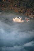 Aerial view of a picturesque alpine village surrounded by tranquil forests and majestic mountains in fog, Amden, St gallen, Switzerland.