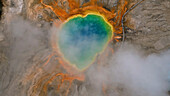 Aerial view of grand prismatic spring with colorful patterns and mist, Yellowstone National Park, Wyoming, United States.