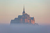 Luftaufnahme der ruhigen und mystischen Abtei, umgeben von Nebel bei Sonnenaufgang, Le Mont-Saint-Michel, Manche, Frankreich.