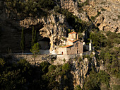 Aerial view of st. michael's church on a cliffside surrounded by trees and rocky landscape, mangalem, berat, albania.