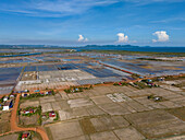 Aerial view of beautiful agricultural fields and a rustic village under a blue sky with clouds, Traeuy Kaoh, Tuek Chhou District, Kampot, Cambodia.