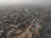 Luftaufnahme einer nebligen und dunstigen Stadtlandschaft mit belebten Gebäuden und Straßen entlang eines Flusses, Lalbagh Thana, Dhaka, Bangladesch.