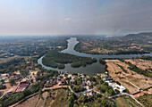 Luftaufnahme des Teuk Chhou Flusses, der sich durch ein malerisches Dorf mit üppigem Grün und ruhigem Ackerland windet, Kampong Kraeng, Provinz Kampot, Kambodscha.