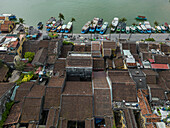 Aerial view of traditional architecture and colorful rooftops along the river with boats, Minh An, Quang Nam, Vietnam.