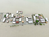 Aerial view of submerged and waterlogged village with floating homes amidst rising waters and flooded streets, Kurigram, Kurigram, Bangladesh.