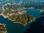 Aerial view of serene Bovilla Lake surrounded by lush green hills and tranquil mountains, Herraj, Tirana, Albania.