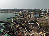 Aerial view of busy industrial activity along the Meghna River with boats and a coal factory, Bhairab, Dhaka, Bangladesh.