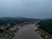 Luftaufnahme eines gewundenen Flusses, umgeben von üppigem Wald, unter einem bewölkten Himmel, Bezirk Pak Beng, Udomsai, Laos.