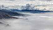 Luftaufnahme von heiterem Küstennebel, der zerklüftete Berge und einen dramatischen Himmel umhüllt, Jenner, Kalifornien, Vereinigte Staaten.