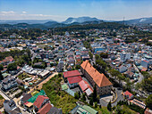 Luftaufnahme einer lebendigen Stadtlandschaft mit Wohngebäuden und üppigem Grün, umgeben von Bergen, Ward 9, Da Lat, Lam Dong, Vietnam.