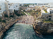 Aerial view of picturesque old town with historic architecture by the beautiful beach and rocky cliffs, Polignano a Mare, Bari, Italy.