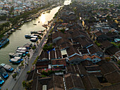Aerial view of beautiful traditional architecture and charming rooftops along a serene river at sunset, Minh An, Quang Nam, Vietnam.