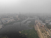 Luftaufnahme des dunstigen und verschmutzten Stadtbilds mit dem Buriganga-Fluss und modernen Gebäuden, Lalbagh Thana, Dhaka, Bangladesch.