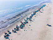 Aerial view of colorful fishing boats on a serene coastline with golden sands and turquoise waters, Cox's Bazar, Cox's Bazar, Bangladesh.