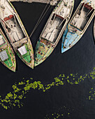 Aerial view of bustling marketplace with boats and cement industries along the river, Amin Bazar, Savar, Dhaka, Bangladesh.
