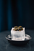 A luxurious portion of beluga caviar on a clear block of ice against a dark, atmospheric background.