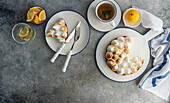 A delicious lemon meringue pie on a plate with a slice served with a cup of herbal tea. Fresh lemon slices in a glass add a refreshing touch to this cosy setting.