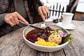 Close-up of a traditional dish served at the Geisleralm restaurant in the Dolomites, Italy The rustic wooden table emphasises the authentic culinary experience